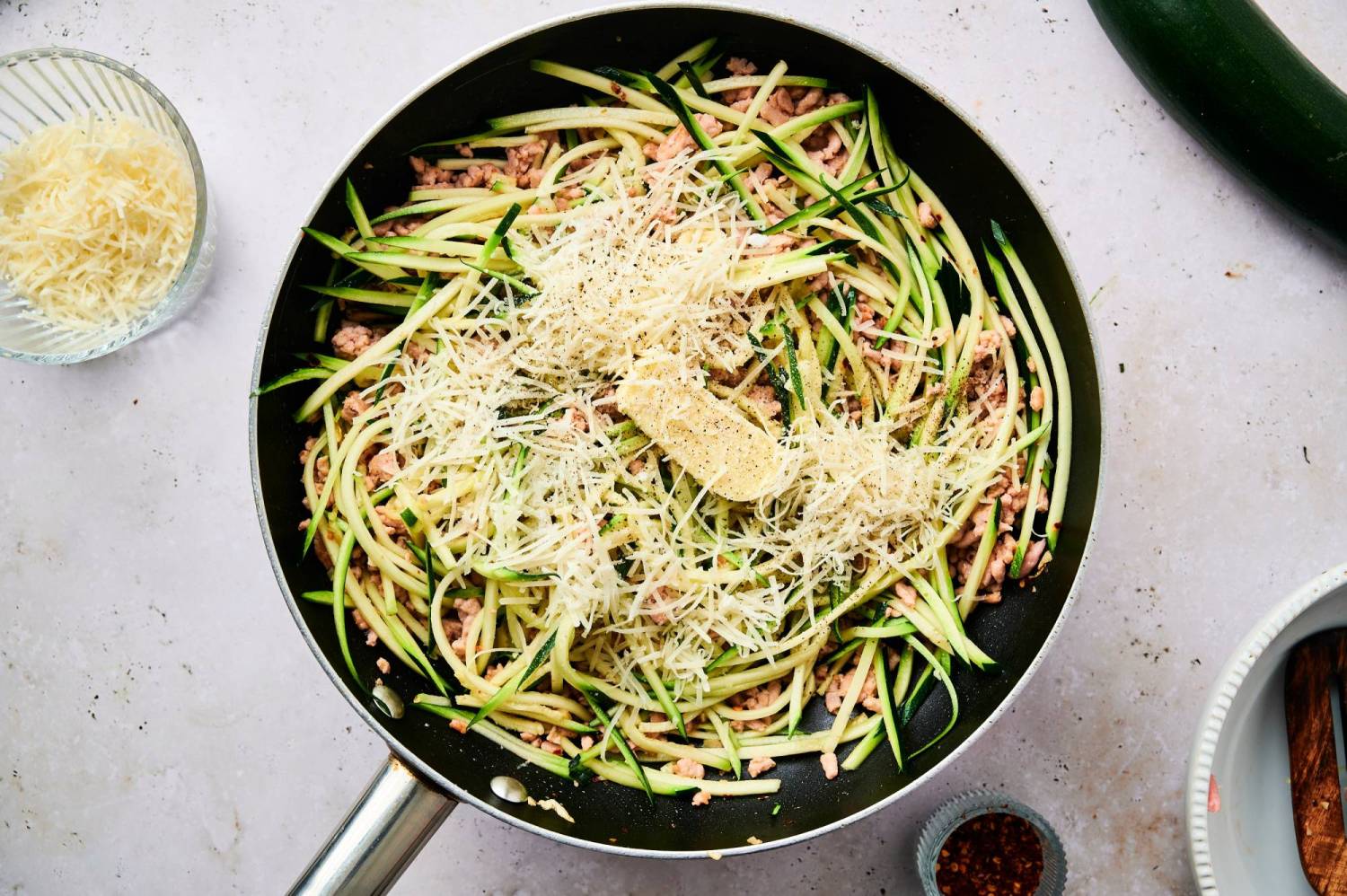 sausage, zucchini noodles, Parmesan cheese, and butter in a skillet.
