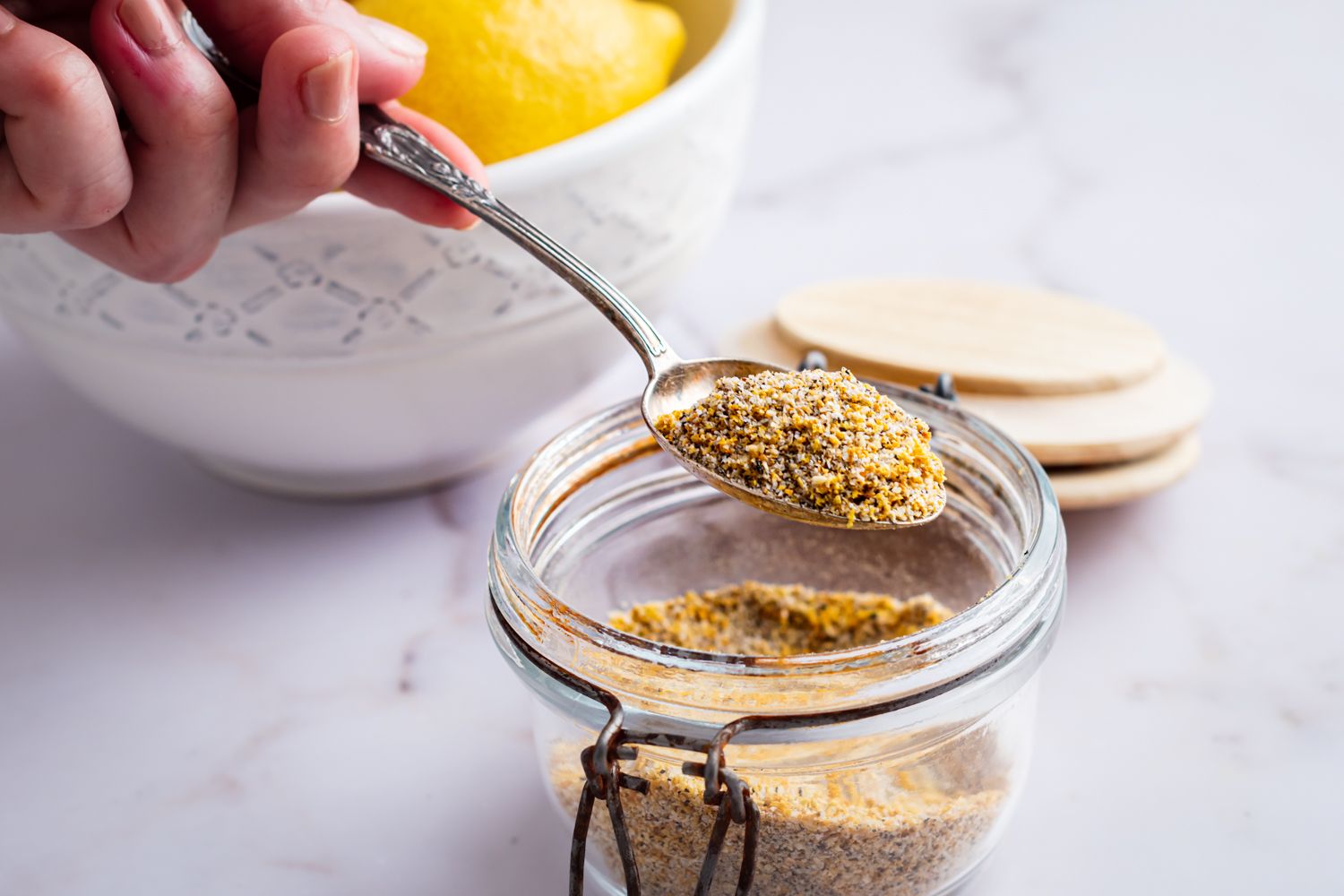 Spoonful of homemade lemon pepper with grains of pepper, salt, and lemon zest.
