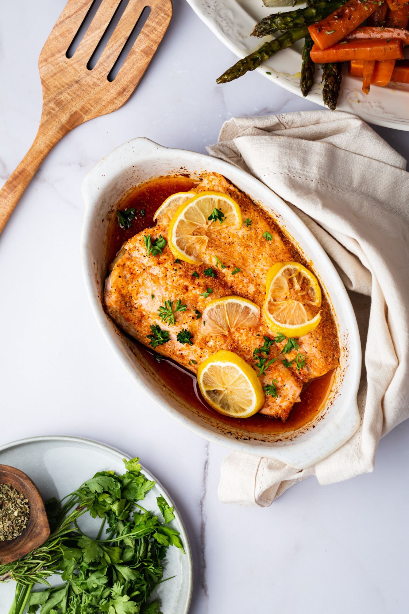 Baked lemon pepper salmon with roasted vegetables and parsley on the side.