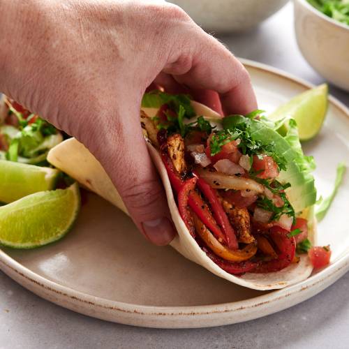 Fajita soft taco with chicken breast, peppers, onions, sour cream, avocado, and salsa