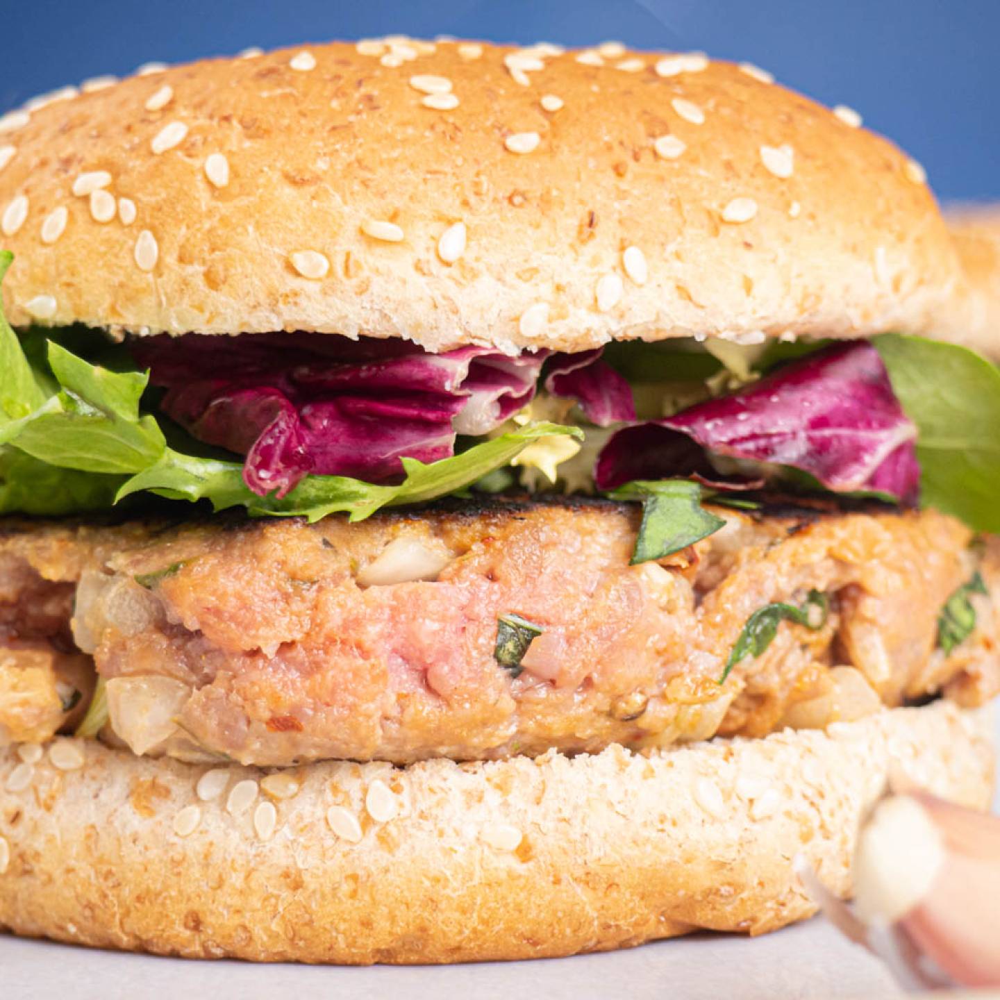 Italian beef burgers on a sesame seed bun with lettuce and tomato.