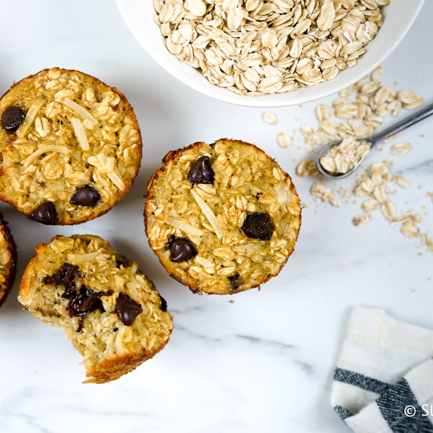 Banana oatmeal muffins with chocolate chips on a marble board.