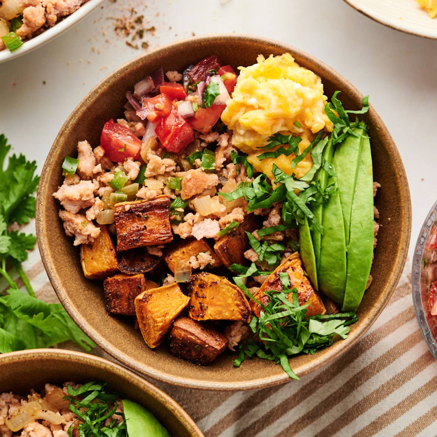 Breakfast burrito bowls with ground turkey, scrambled eggs, roasted sweet potatoes, avocado, pico de gallo, and cilantro.