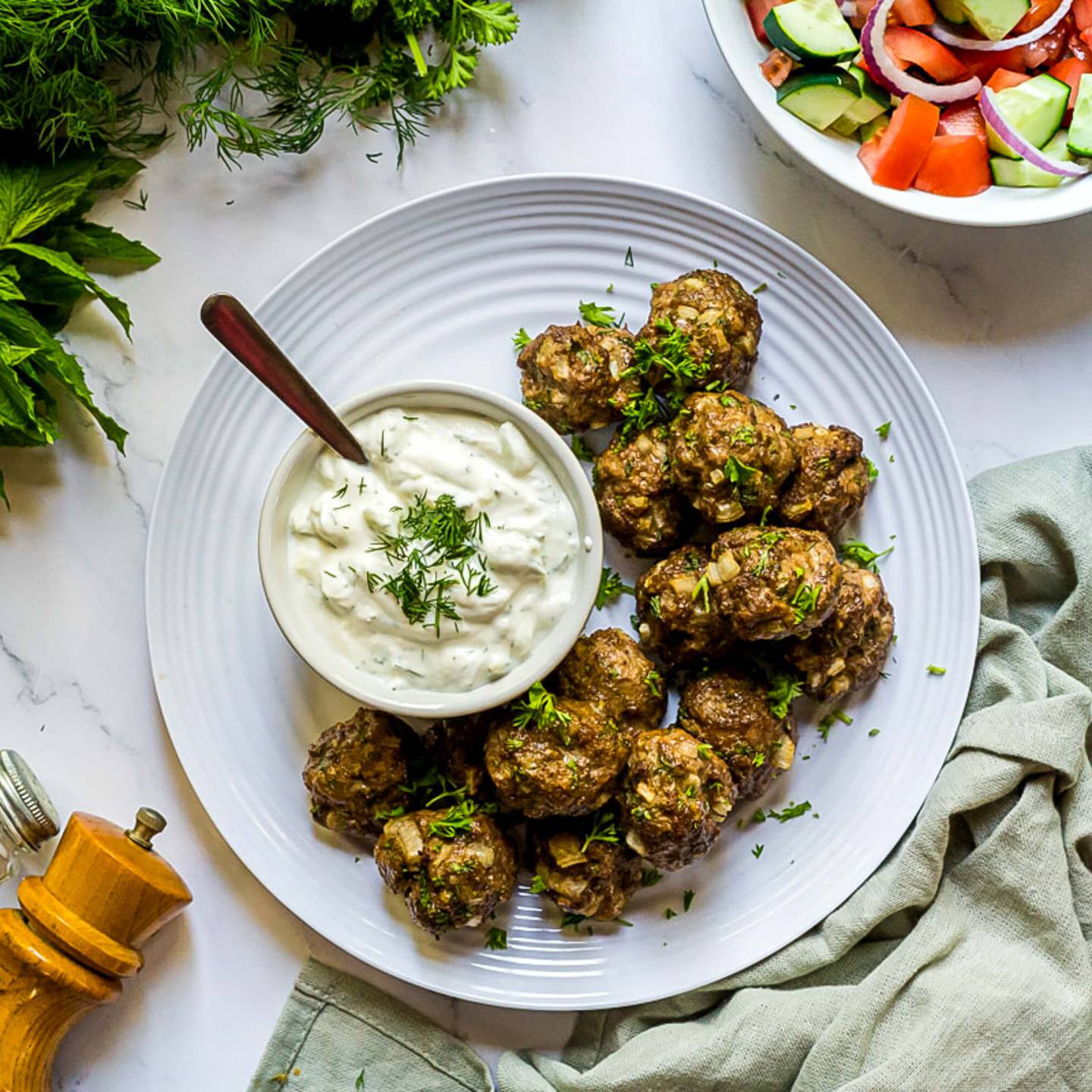 Turkish kofte meatballs made with ground lamb, beef, herbs, and spices served with yogurt sauce and salad.