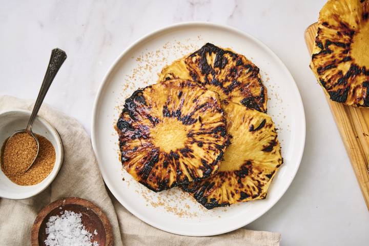 Grilled pineapple with brown sugar and flaky sea salt on a plate. 