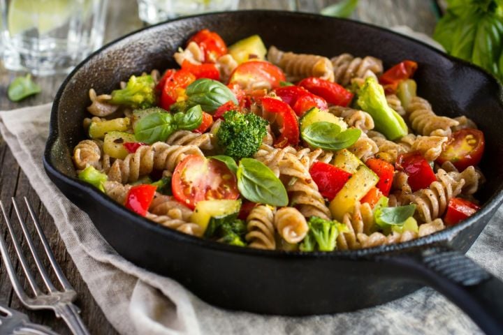 Vegetable scampi in a bowl with broccoli, tomatoes, zucchini, and a garlic butter sauce. 