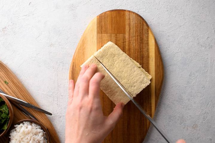 Tofu being pressed and sliced into slabs.