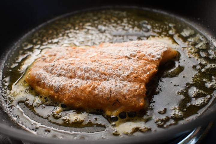 Cod being pan seared in a hot skillet.