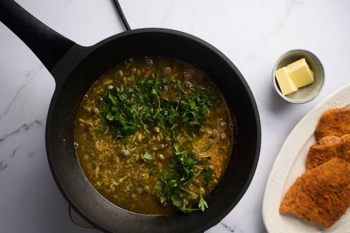White wine pan sauce with capers and garlic in a skillet.