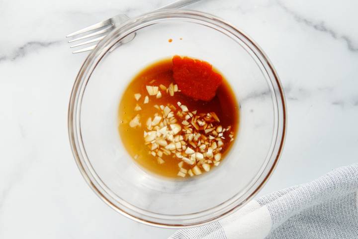 Honey sriracha marinade with garlic in a glass bowl.
