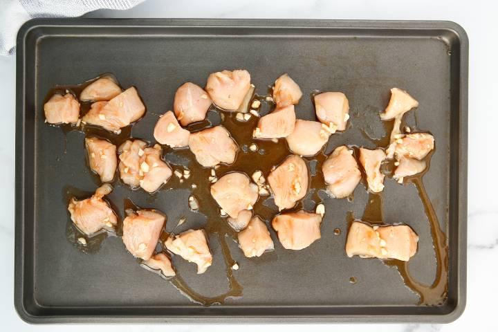 Chicken breast with honey and Sriracha on a baking sheet.