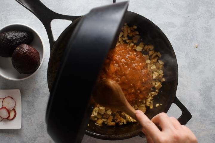 Sofritas sauce being added to a skillet with crispy tofu.