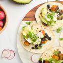 Butternut squash black bean tacos on corn tortillas with cilantro, cheese, avocado, and onions.