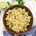 Cilantro lime quinoa in a bowl with cilantro leaves, lime zest, garlic, and onion.