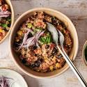 Bowls of cooked Mexican quinoa topped with fresh red onion slices and chopped cilantro, ready to be served with additional toppings on the side.