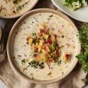 A bowl of creamy slow cooker roasted corn chowder topped with roasted vegetables, fresh thyme, and black pepper.