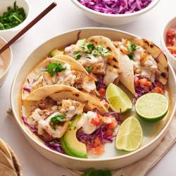 Grilled fish tacos with grilled white fish, shredded cabbage, avocado, pico de gallo, and creamy white fish taco sauce.