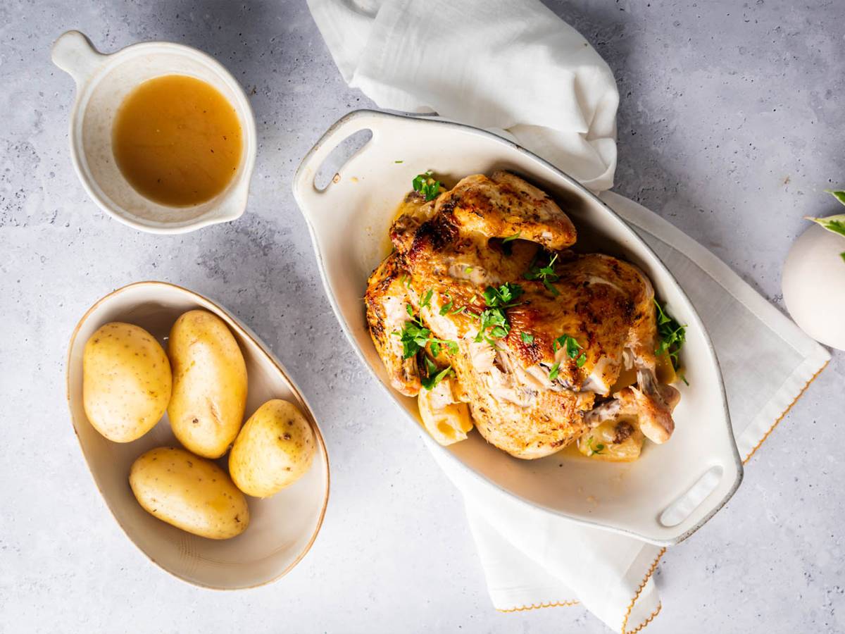 Slow cooker rotisserie chicken with a homemade spice rub, lemon, and parsley with potatoes on the side.